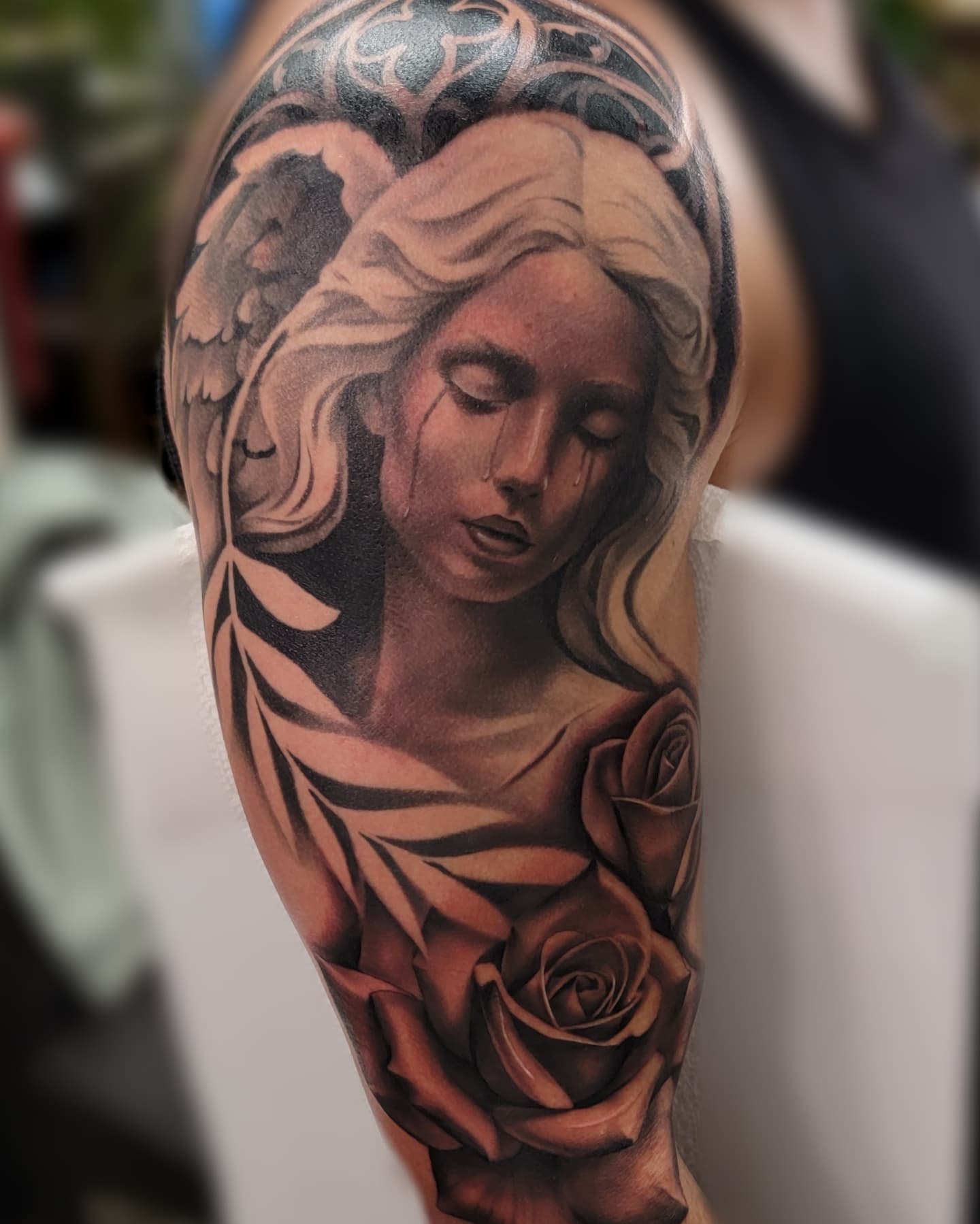 Black-and-grey angel and roses upper-arm tattoo