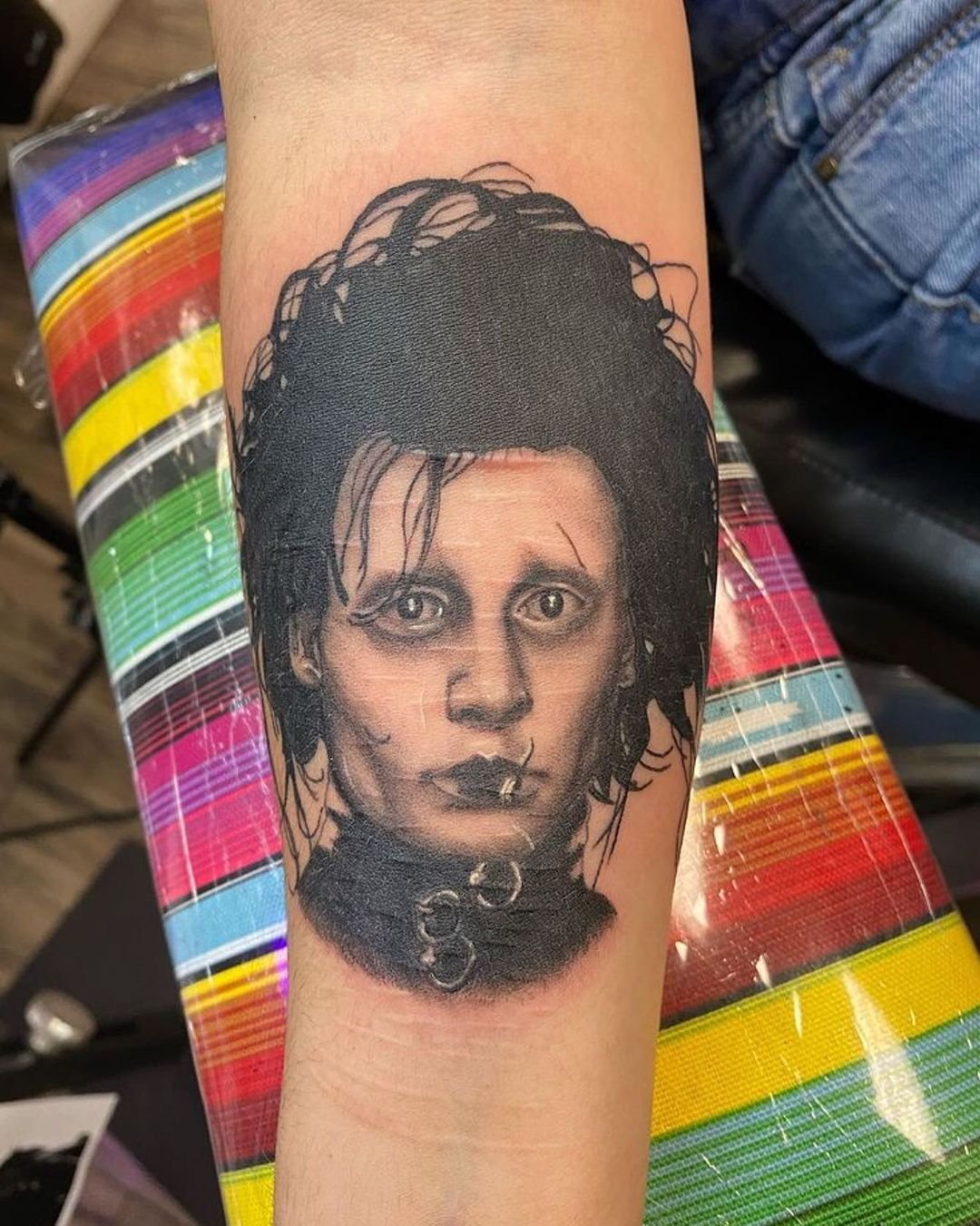 Black-and-grey Edward Scissorhands forearm portrait tattoo