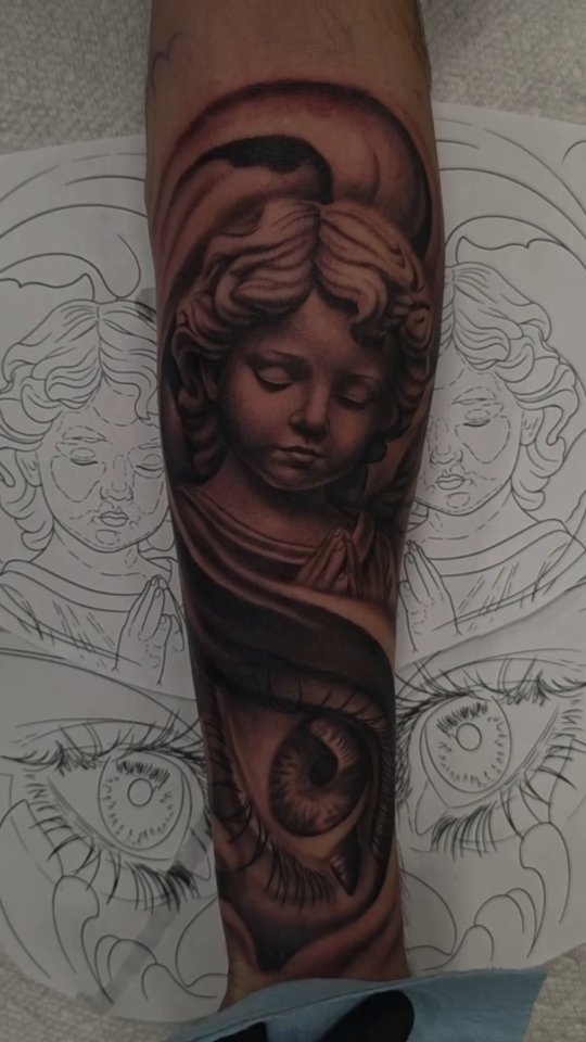 Black-and-grey praying cherub and realistic eye tattoo