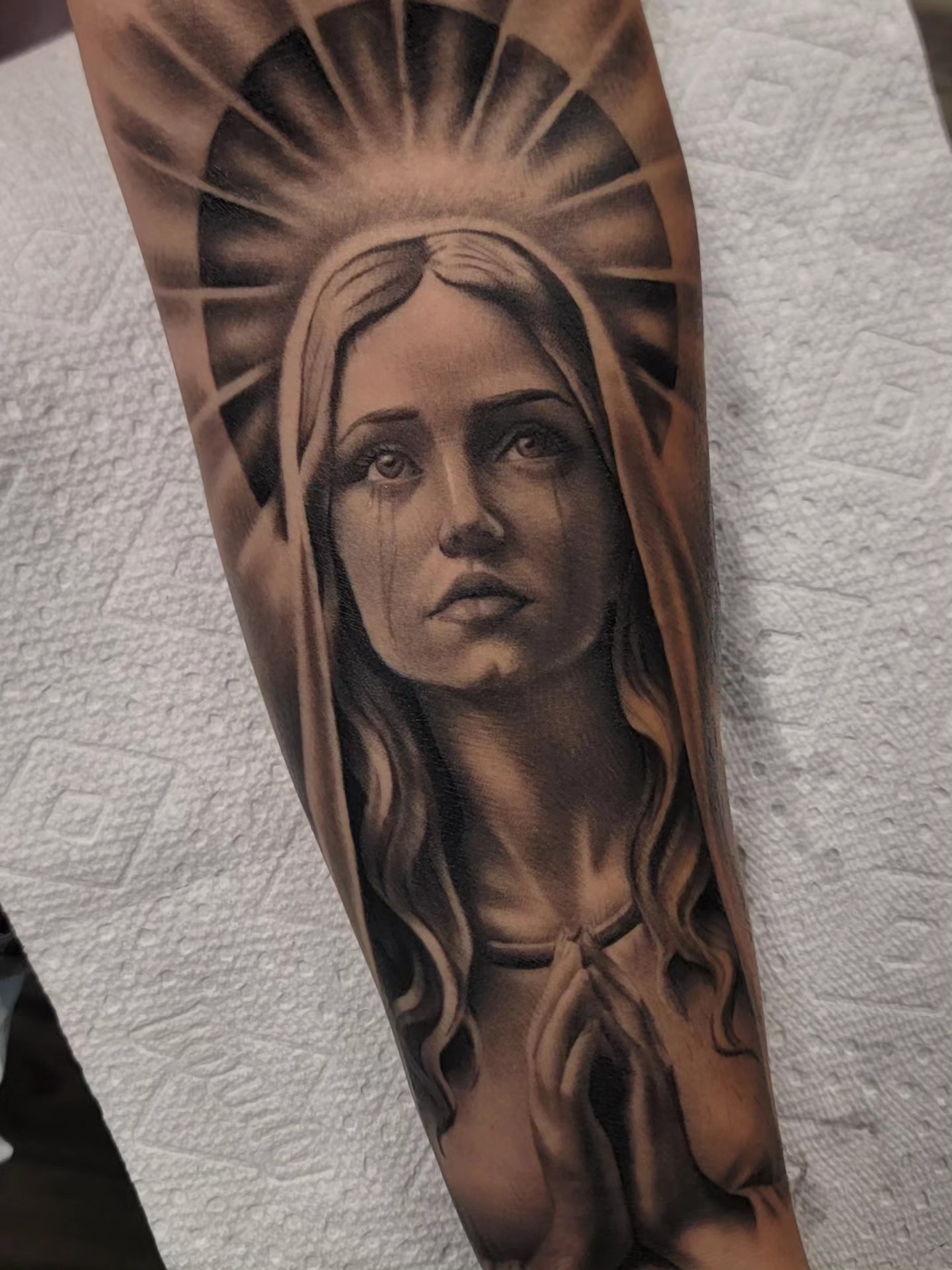 Black-and-grey praying woman tattoo with radiating lines