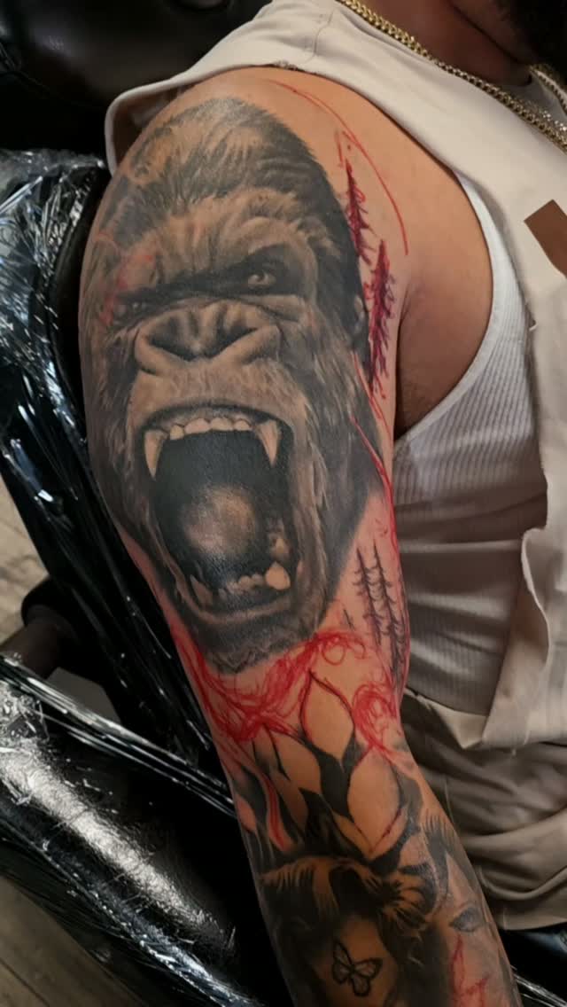 Black-and-grey roaring gorilla upper-arm tattoo