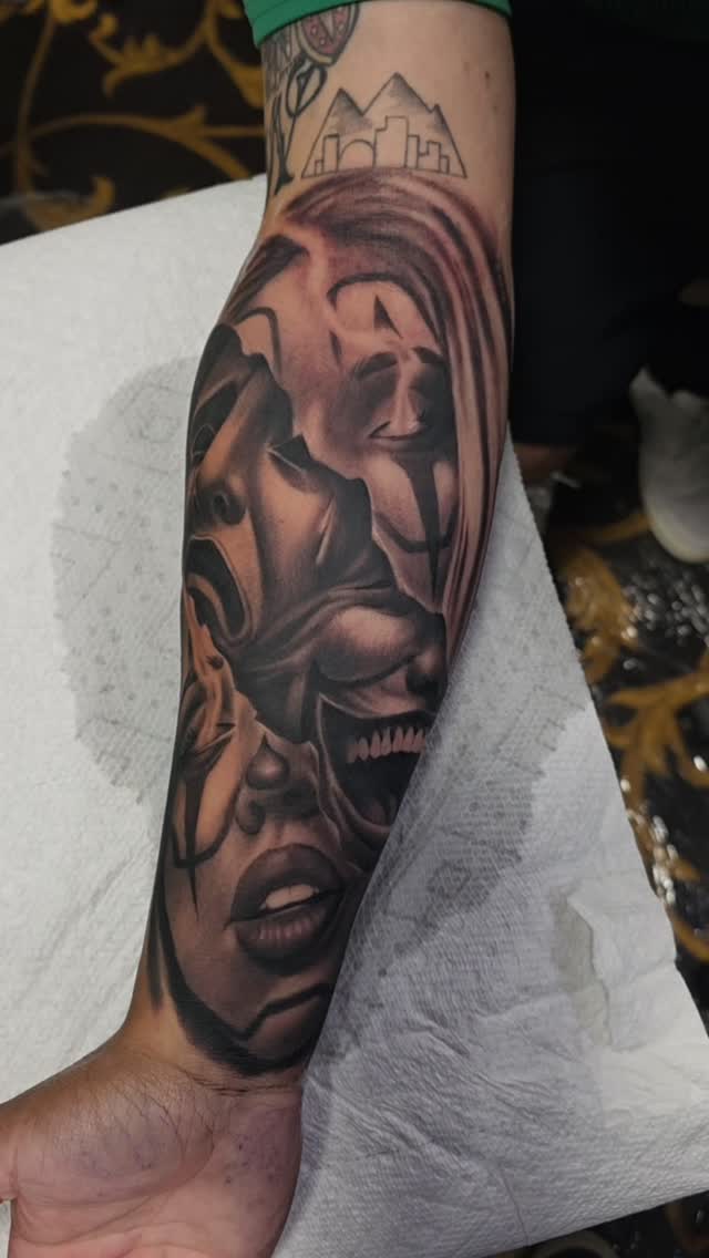 Black-and-grey surreal layered faces forearm tattoo