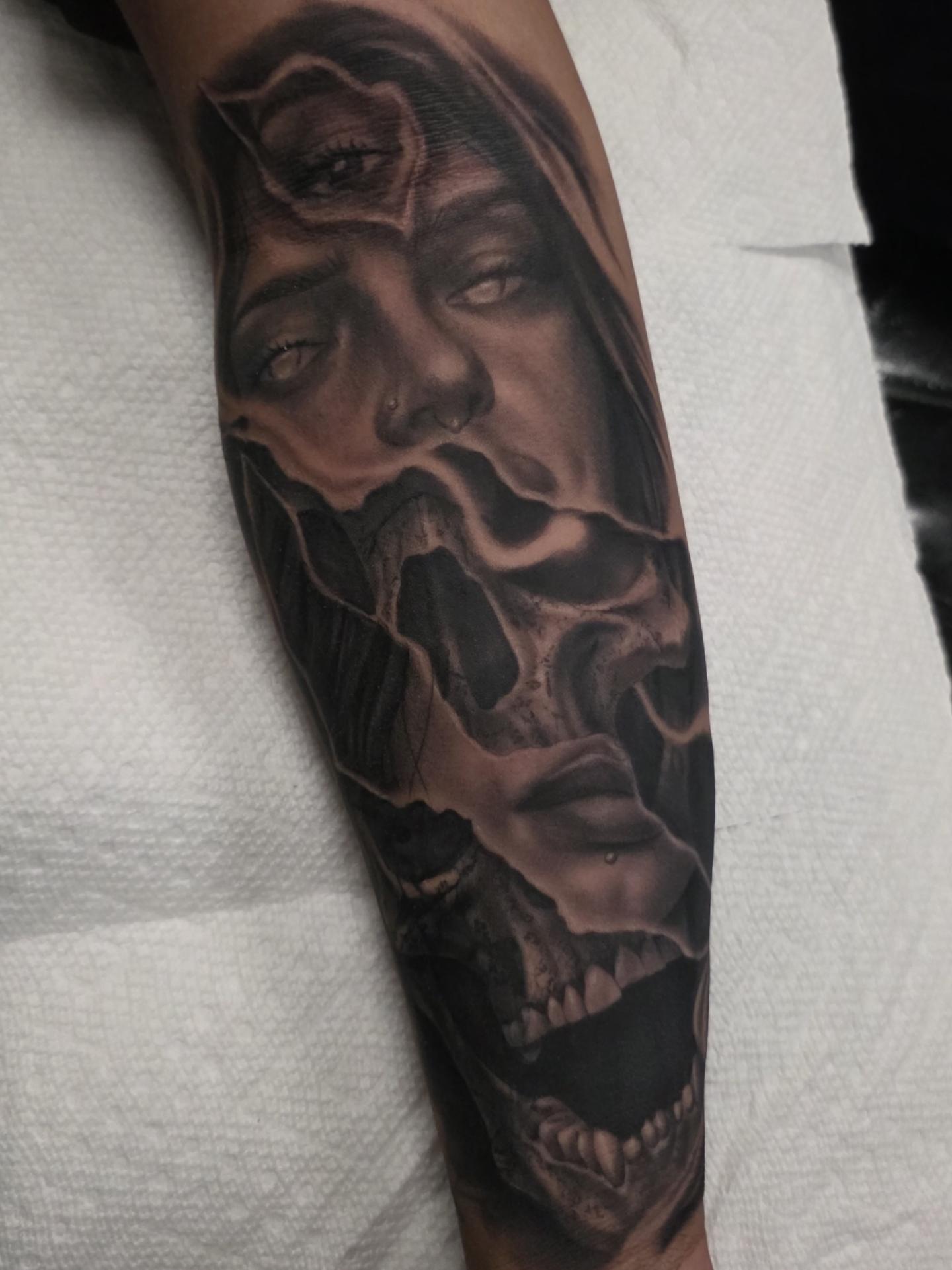 Black-and-grey three-eyed woman and skulls tattoo